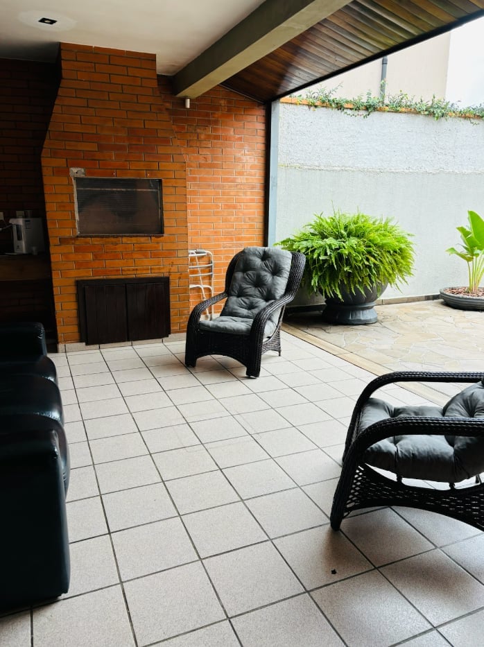 Espaço gourmet com churrasqueira de tijolos e poltronas